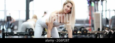 Athlete stands in rack on simulator and holds dumbbell Stock Photo