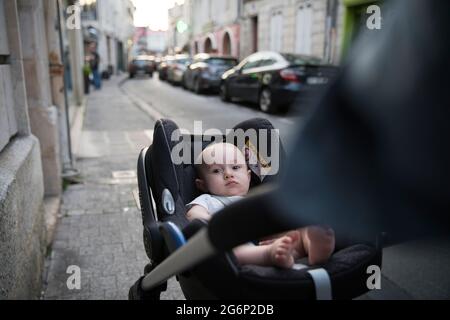 A baby being pushed down a street in a pushchair Stock Photo