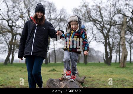 A mother helping her child walk along a log Stock Photo
