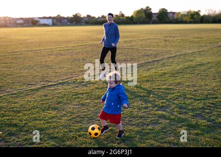 A mother playing football with her young son Stock Photo