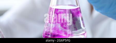 Closeup of test tube with pink liquid in hand of scientist Stock Photo