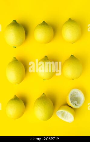 9 aligned lemons, one cut and squeezed, on a yellow background Stock Photo