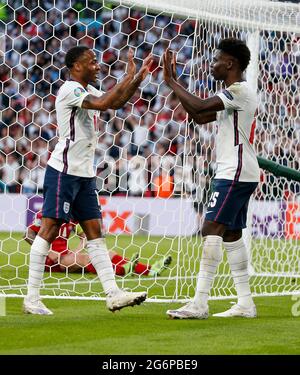 London, Britain. 7th July, 2021. England's Bukayo Saka (R) and Raheem Sterling celebrate Denmark's own goal during the semifinal between England and Denmark at the UEFA EURO 2020 in London, Britain, on July 7, 2021. Credit: Han Yan/Xinhua/Alamy Live News Stock Photo
