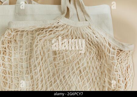 Beige reusable cotton mesh bags on beige background. Eco-friendly shopping bag. Close up. Zero waste grocery concept. Sustainable Stock Photo