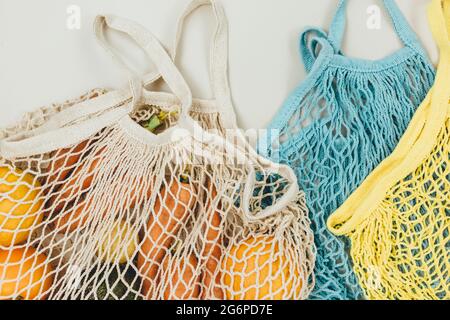 Fresh vegetables in a blue beige reusable cotton mesh bag on beige background. Eco-friendly shopping bag. Zero waste grocery concept. Sustainable lifestyle Stock Photo