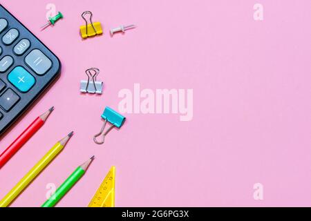 Back to school concept. School and office supplies on a pink background. Multi-colored stationery and black calculator Stock Photo