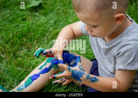 The child draws a pattern on the leg. A funny drawing with bright colors on the body. Selective focus Stock Photo