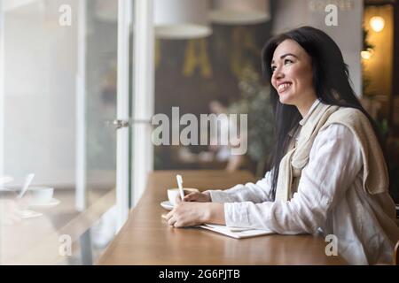 Closeup female hands making paper notes in notepad use pen table cafeteria writing diary, planning Stock Photo