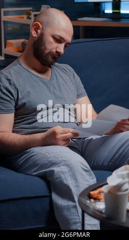 Confused frustrated stressed young man reading letter, debt notification, bad financial report, money problem, eviction notice. Shocked, worried tenant by warning document for unpaid bank bills Stock Photo