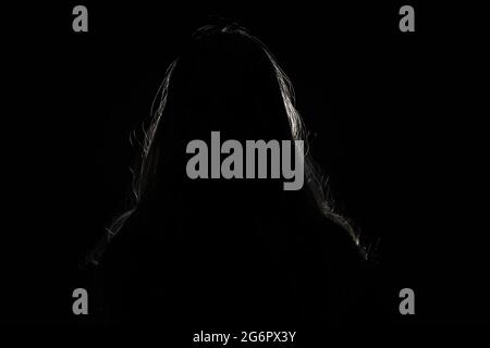 anonymous woman hiding face and identy in the dark shadow Stock Photo