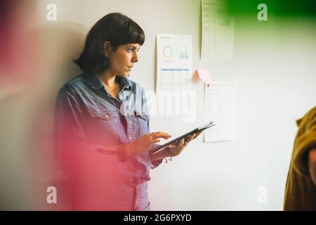 Woman holding digital tablet in office. Female professional with a tablet computer standing at workplace. Stock Photo