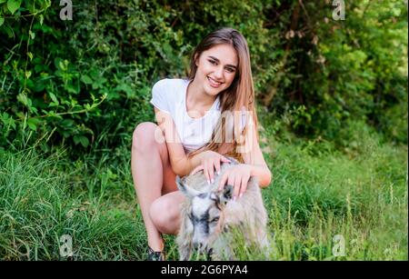 Woman play cute goat. Farm and farming concept. Village animals. Protect animals. Veterinarian occupation. Treating animals at farm. United with Stock Photo