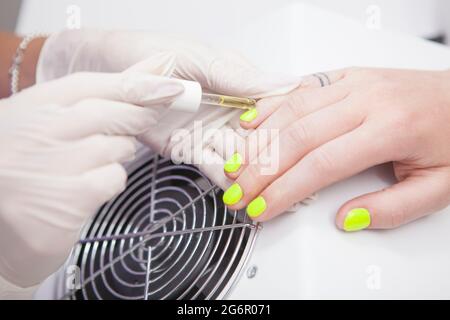 Unrecognizable woman getting cuticle oil applied after manicure by nail technician Stock Photo