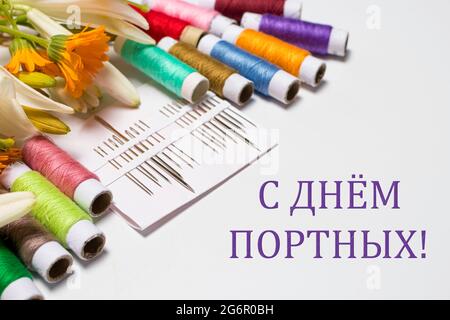Greeting card with multi-colored threads and the text in Russian. Translation: Happy Tailors Day. For the holiday of a seamstress, tailor, atelier Stock Photo