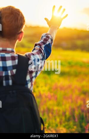 Back view, Human hand, tourist covering sunlight, Sun shining through hand, Human hand and sun, travel concept, tourism Stock Photo