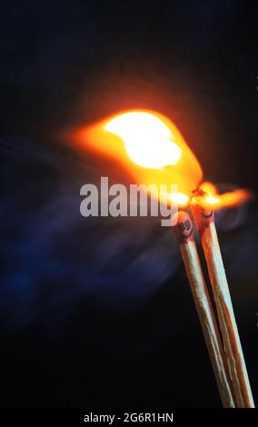 A couple of matches burning together with heat flame isolated on a black background. Stock Photo