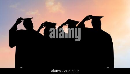 Composition of silhouettes of graduating students in caps and gowns against sunset sky Stock Photo