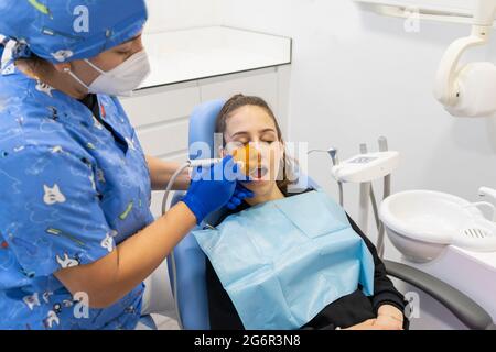 Female doctor dentist using dental curing UV lamp on teeth of patient Stock Photo