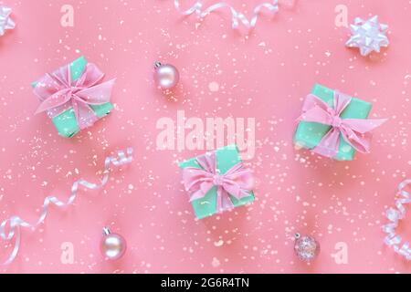 Three green present boxes with bow on pink background with boubles and confetti. Christmas concept. Top view, flat lay Stock Photo