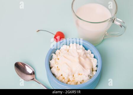 Cottage cheese in a blue bowl with sour cream and honey, a cup with milk. Morning breakfast. Stock Photo