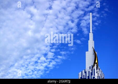White Altocumulus Clouds Scattered on Vivid Blue Sky with Top of an Amazing Modern Skyscraper Stock Photo