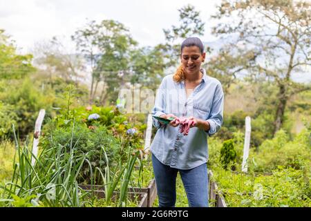 woman holding gardening tools in her hands in her vegetable garden Stock Photo