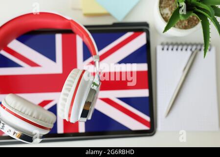 Tablet with image of British flag with headphones and notebook with pen lie on table Stock Photo