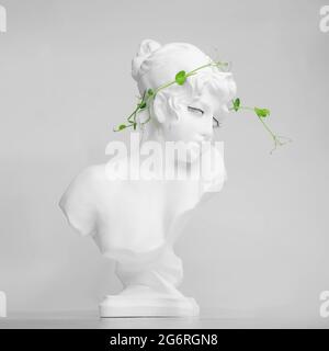 Healthy food and diet minimalism concept. statue made of plaster with micro greens of young sprout of peas on white background. Stock Photo