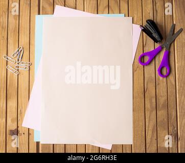 Empty Paper Clipped Together Lying Flat On A Table With Pencils And Stapler. Office Stationery Blank Sheet Of Stacked Papers With Clips Placed On A Stock Photo