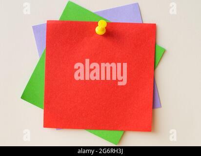 Colorful Paper Notes Stacked Together And Pinned On The Wall. Different Colored Sheets Of Note Attached On A Plain Wallpaper With A Pin. Stock Photo