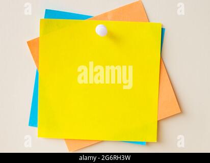 Colorful Paper Notes Stacked Together And Pinned On The Wall. Different Colored Sheets Of Note Attached On A Plain Wallpaper With A Pin. Stock Photo