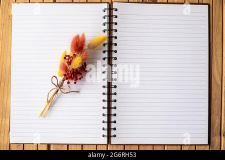 Blank Open Notebook With A Colorful Flower On Top And Placed On A Wooden Desk. Empty Opened Spiral Notepad With A Floret In The Middle Placed On A Stock Photo