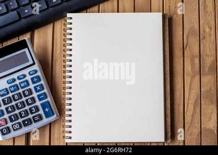 Blank Opened Spiral Notebook With A Calculator Keyboard Pen Placed Over Table. Empty Lined Notepad And Pencil On Top Of A Desk With A Calculation Stock Photo