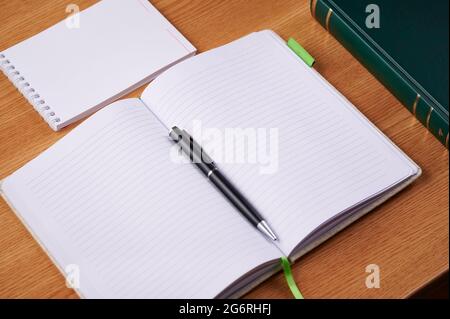 Plain Blank Open Notebooks With Stack Of Pens Inside Container Placed On Top Of A Table. Simple Empty Lined Notepads Beside A Holder Of Colorful Stock Photo