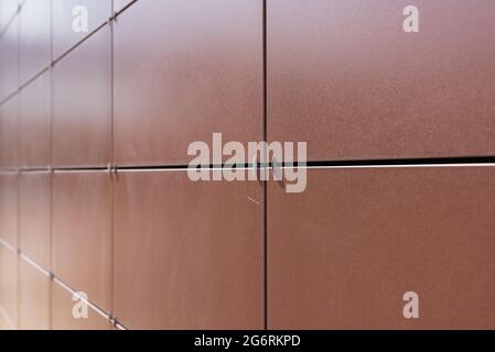 Background texture of rectangular smooth brown tiles. Stone street covering of wall, masonry of building.Brown stone panels for ventilated walls or fa Stock Photo