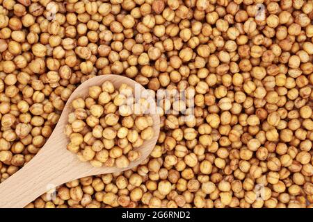 Spicy roasted organic chickpeas for a healthy snack in a wooden spoon and forming a background. High in fibre, protein, vitamins and minerals Stock Photo