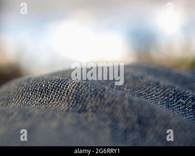Macro photography of the folds of a pair of jeans  looking like hills against the cloudy sky. Stock Photo