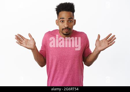 Nothing to say. Clueless african american guy raising empty hands up, shrugging shoulders and looking unaware, dont understand, standing against white Stock Photo