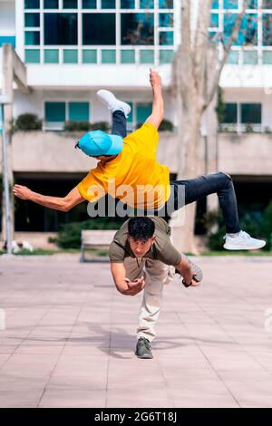 Two multi-ethnic friends dancing in the park and doing break dance moves. Stock Photo