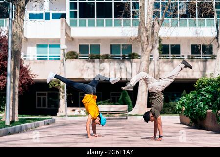 Two multi-ethnic friends dancing in the park and doing break dance moves. Stock Photo