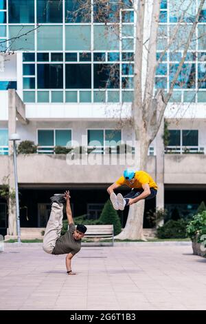 Two multi-ethnic friends dancing in the park and doing break dance moves. Stock Photo