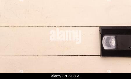 white wooden background with an old black vhs tape on one side Stock Photo
