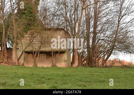 Front view on old concrete pillbox bunker or fallout shelter among trees that was made to prepare Switzerland for war or to protect the Swiss people. Stock Photo