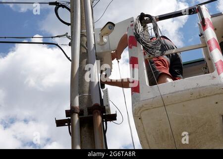 Man making maintenance of a security camera to monitor public places in a village in Slovakia. The man is standing on a hydraulic platform. Stock Photo