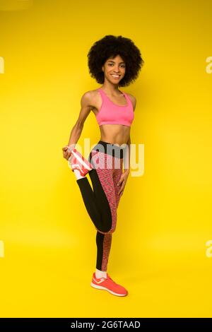 A young pretty curly-haired mulatta doing legs stretching Stock Photo