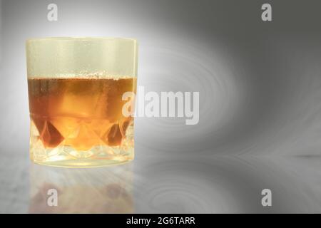 Misted glass with drops of water and whiskey with ice. Sweaty glass of whiskey with ice on table with copy space Stock Photo