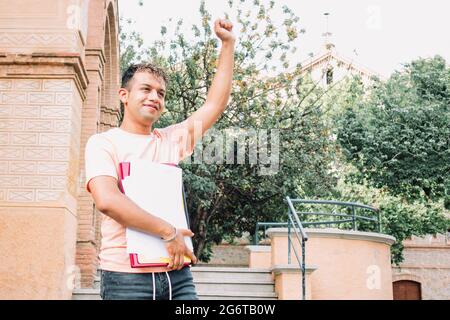Young latino guy celebrating going back to the university or a student having success after an exam. Positive attitude concept Stock Photo