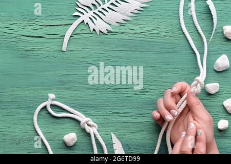 Abstract grungy mint green wooden background with exotic paper leaves made of paper and white stones. Copy-space, place for your text. Flat lay, top Stock Photo
