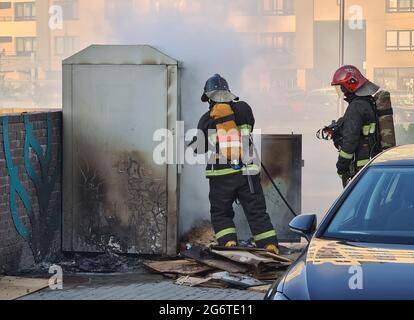 Firefighters extinguishing garbage can fire in car park