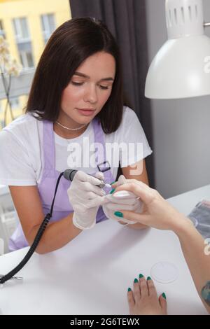 Top view vertical shot of a female manicurist using nail drill, working at her salon Stock Photo